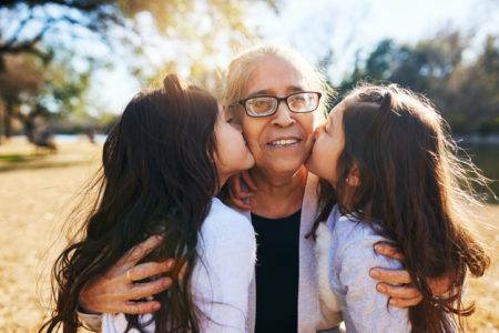 grandmother getting kissed on the cheeks by her two adorable granddaughters